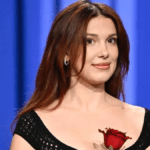 Millie Bobby Brown sheer black knit catsuit, Millie Bobby Brown naked dressing Tonight Show, Millie Bobby Brown braless fashion statement, Millie Bobby Brown auburn hair transformation, Millie Bobby Brown Stranger Things Season 5 press circuit, Millie Bobby Brown crochet knit jumpsuit look, Millie Bobby Brown girly goth naked dress style, Millie Bobby Brown Bronx Banco Liora gown fishnet, Millie Bobby Brown daring red carpet outfits 2025, Millie Bobby Brown lingerie inspired fashion trend